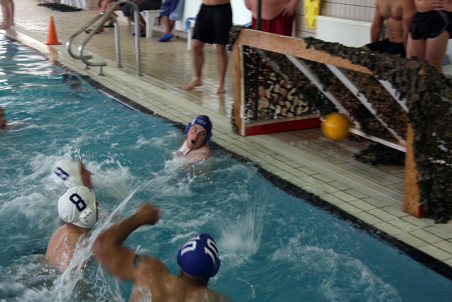 A player winding up to shoot on the water polo goal